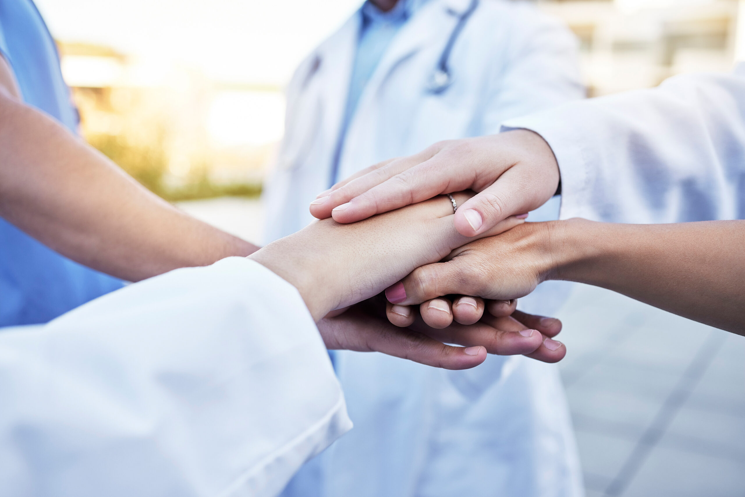 A shot of 5 doctors hand piled on top of each other, in a team break formation